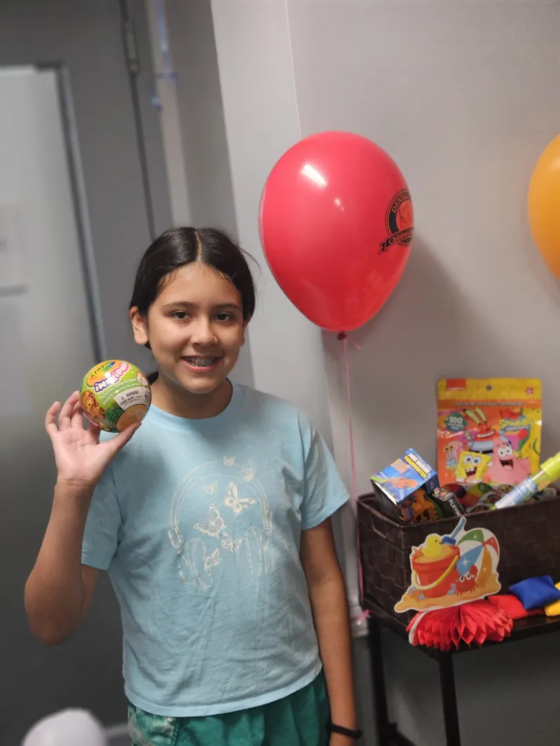 A Dental Care Kids patient with the prize and balloon she picked after her visit