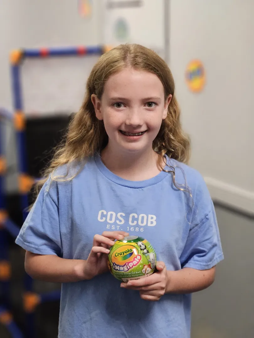 A Dental Care Kids patient holding up the prize token she earned at her visit