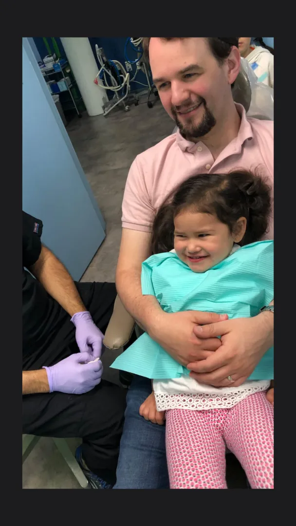 A Dental Care Kids team member comforting a young patient in the chair