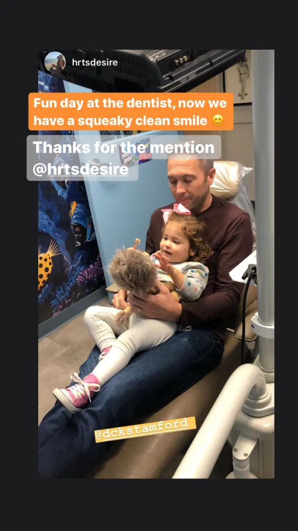 A Dental Care Kids team member holding a young patient during a visit
