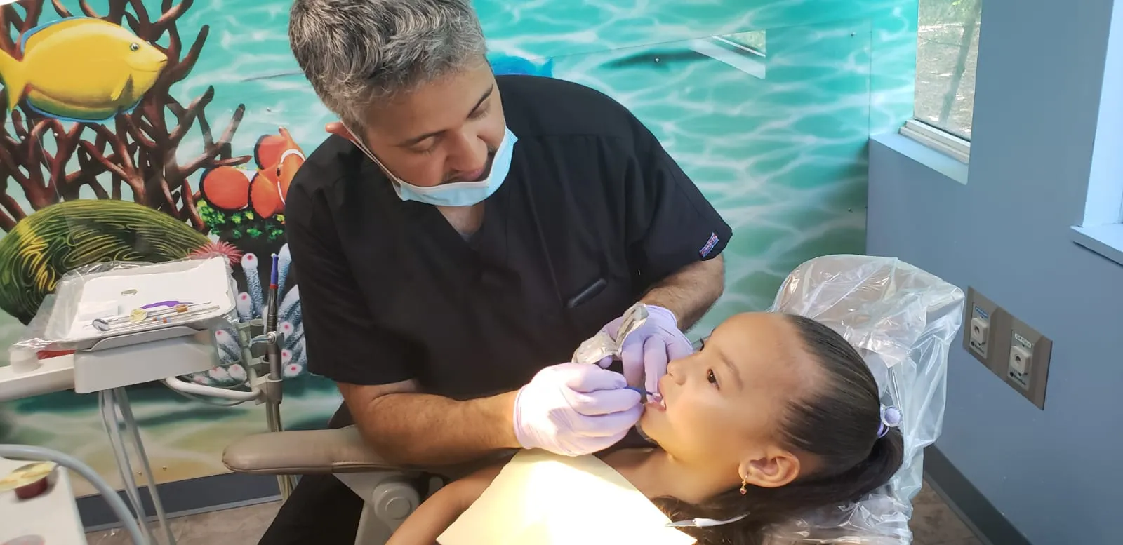 A Dental Care Kids dentist treating a young patient in the chair