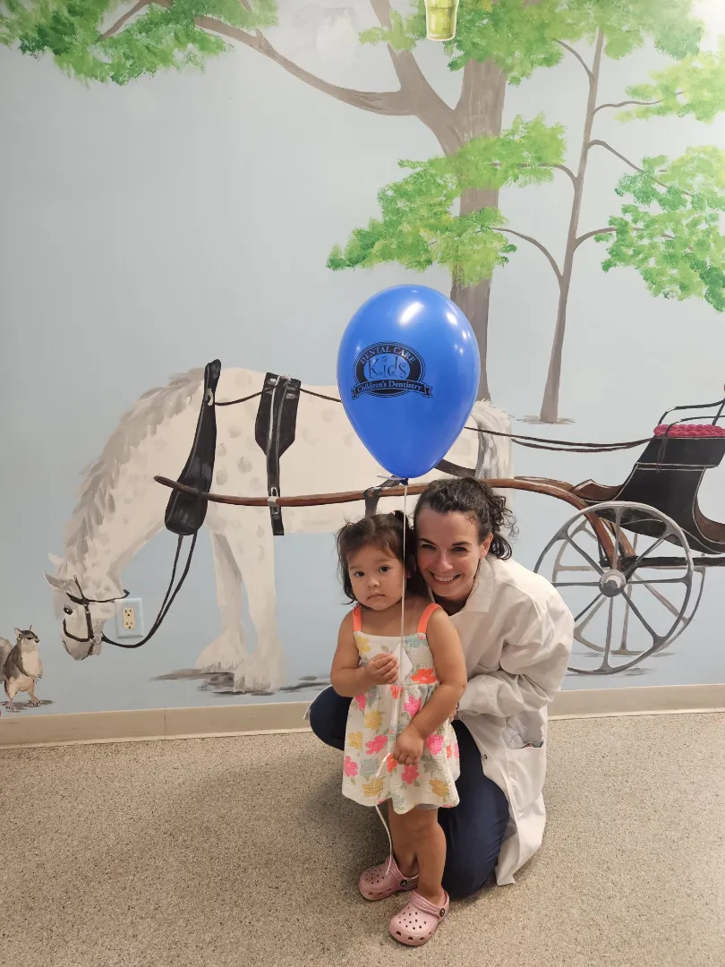 A Dental Care Kids patient with a balloon by the horse mural