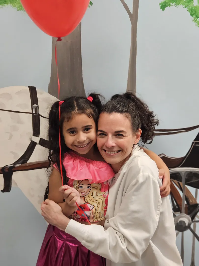 A Dental Care Kids patient hugging a team member after her appointment