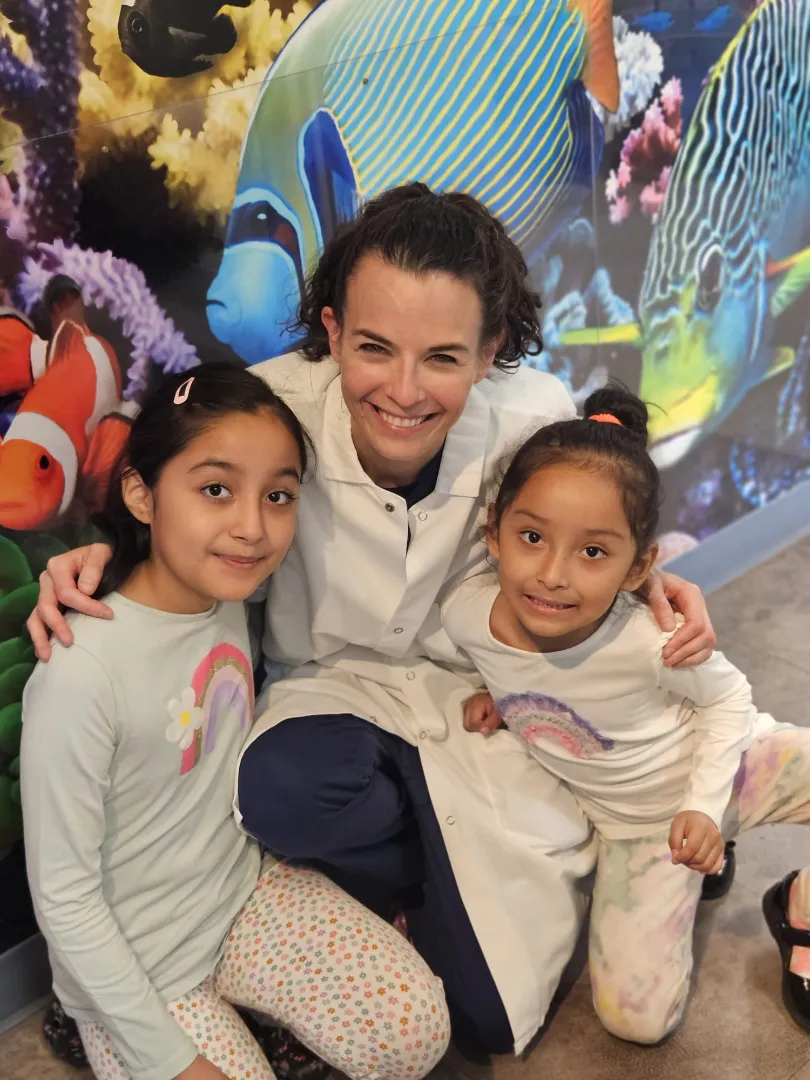Dental Care Kids patients with a team member by the mural wall