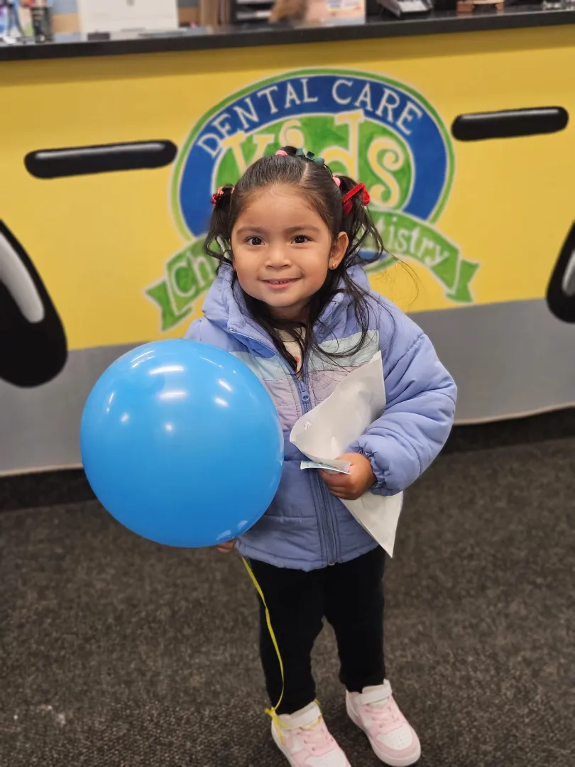 A Dental Care Kids patient holding a blue balloon in the waiting area