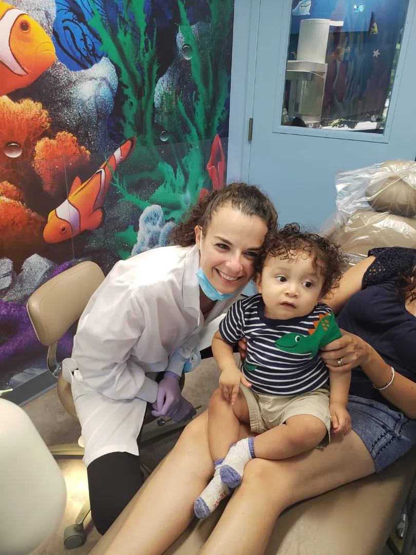 A Dental Care Kids team member holding a baby by the clownfish mural