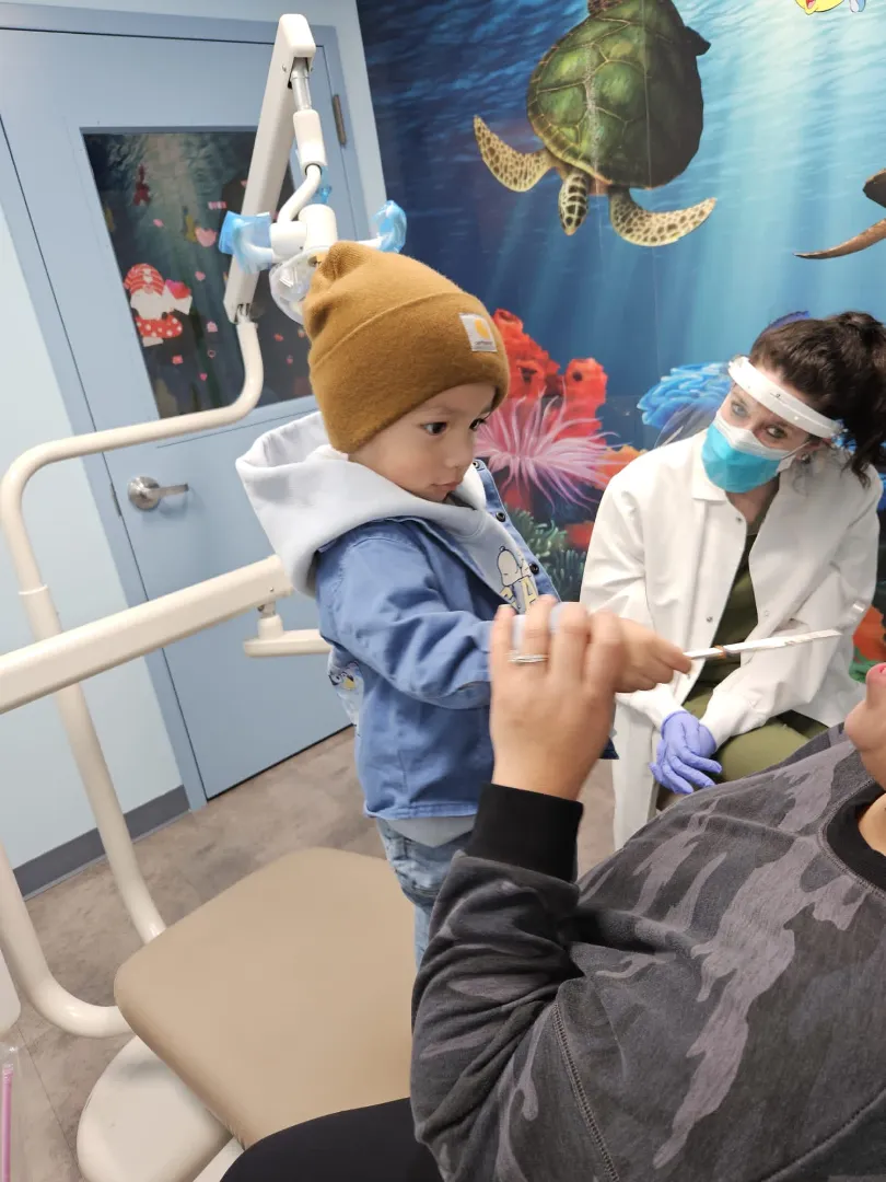 A Dental Care Kids clinician treating a young patient gently in the chair