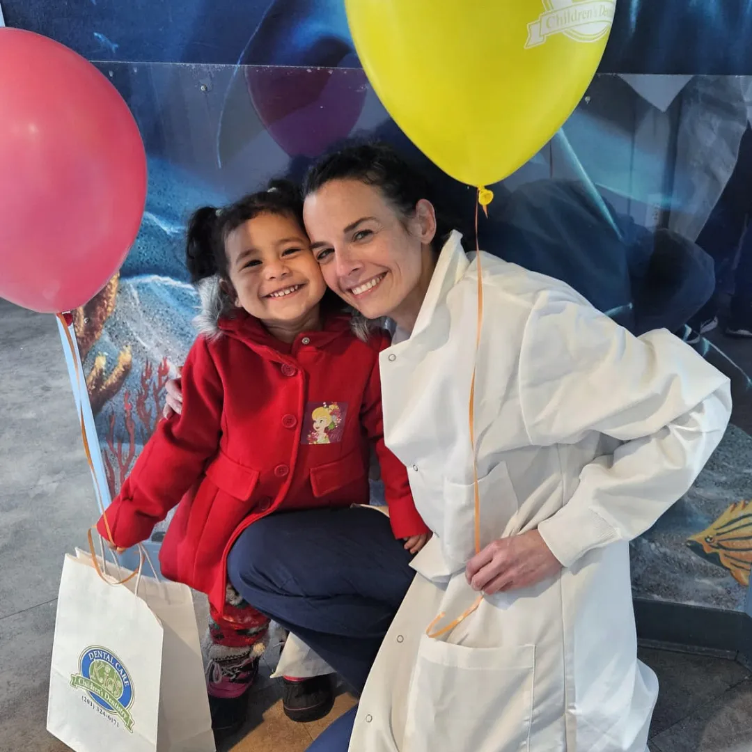 A Dental Care Kids patient with balloons and a team member
