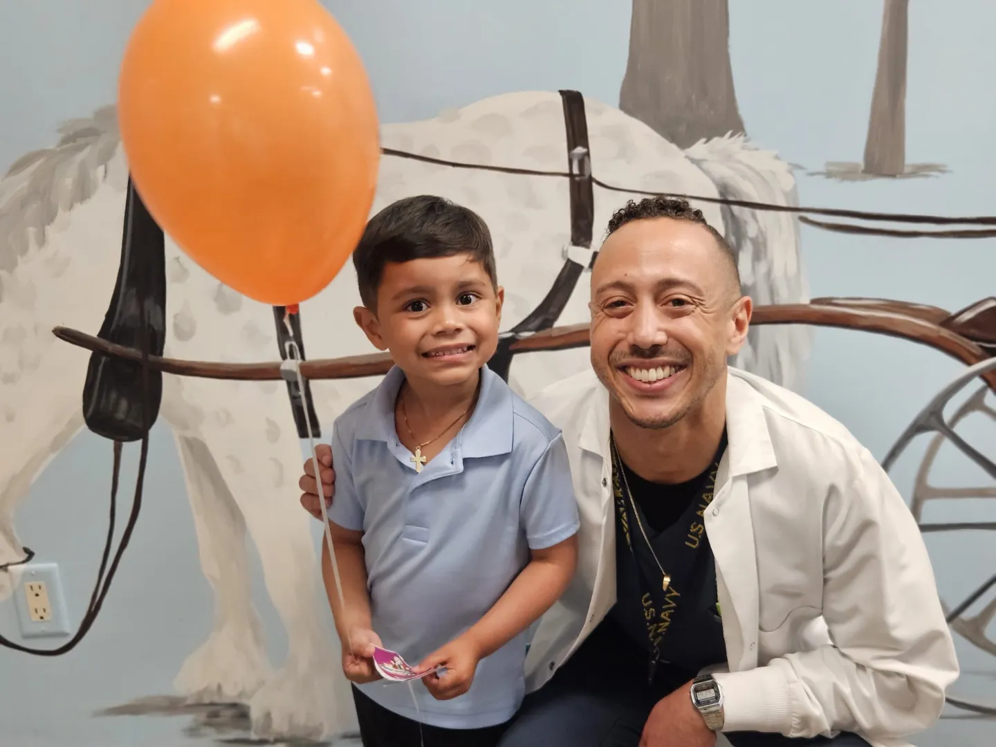 A Dental Care Kids patient holding a balloon beside a team member