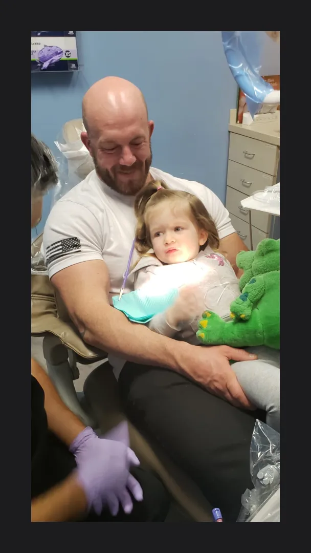 A Dental Care Kids team member comforting a small child in the treatment chair