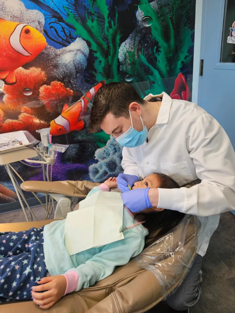 A Dental Care Kids dentist treating a patient in the operatory