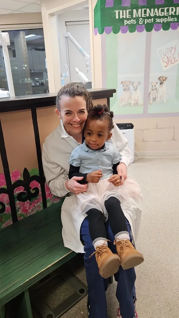 A Dental Care Kids team member holding a young patient after treatment
