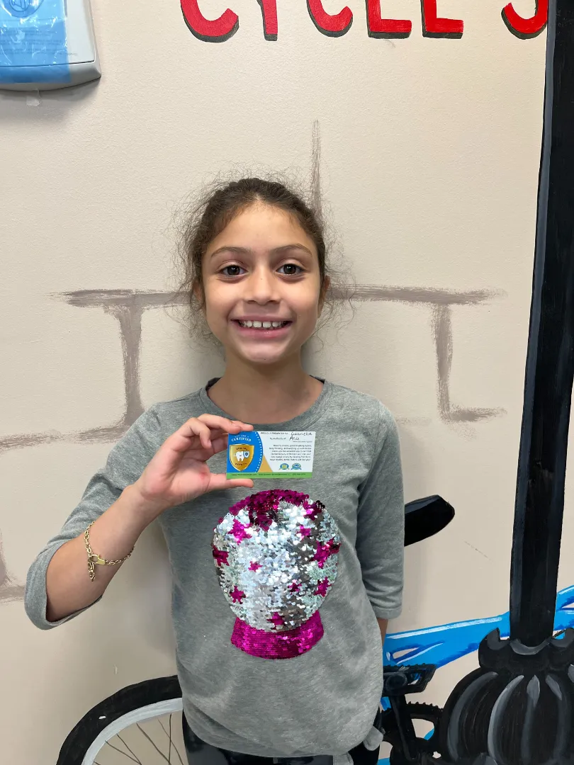 A Dental Care Kids patient holding up the token she earned at her visit
