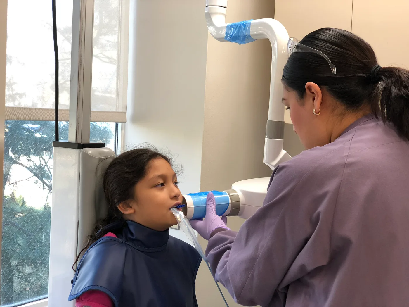 A Dental Care Kids team member taking a low-dose digital X-ray for a young patient
